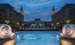 a swimming pool in front of a large building at Hilton Qingdao Golden Beach in Qingdao +102 photos