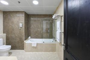 a bathroom with a bath tub and a toilet at Saray Musheireb Hotel Suites and Apartment in Doha