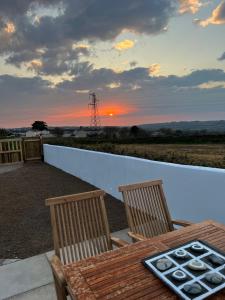 a table and chairs with a sunset in the background at Citrus Chalet in Redruth