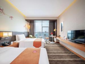 a hotel room with two beds and a flat screen tv at Hilton Garden Inn Chengdu Huayang in Chengdu