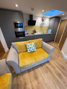 a living room with a yellow couch and a kitchen at Citrus Chalet in Redruth