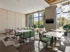 a restaurant with tables and chairs and a flat screen tv at Hilton Garden Inn Tianjin Huayuan in Tianjin