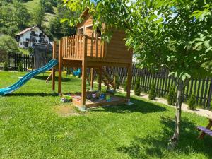 a wooden playground with a slide in a yard at Balkanic Villa Bran in Bran