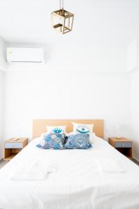 una camera da letto con un grande letto bianco con cuscini blu di Ennea Suites-Flame suite a Flámbouras
