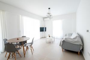 Habitación blanca con mesa, sillas y cama en Ennea Suites-Flame suite en Flámbouras