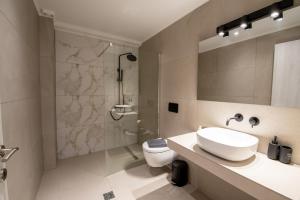 a bathroom with a sink and a shower and a toilet at Ennea Suites-Flame suite in Flámbouras