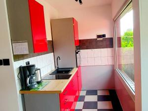 a small kitchen with red cabinets and a sink at holiday home, Nowe Warpno in Nowe Warpno