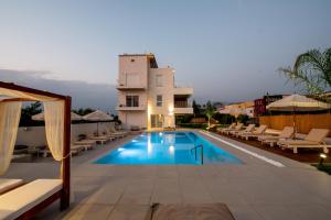 a swimming pool with lounge chairs and a building at Ennea Suites-Flame suite in Flámbouras