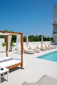 a hotel pool with chaise lounge chairs and a swimming pool at Ennea Suites-Flame suite in Flámbouras