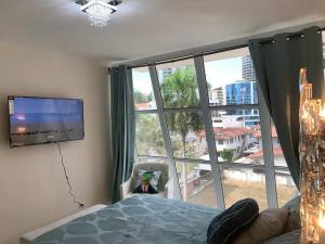 een slaapkamer met een groot raam en een televisie bij 5A - Boutique Apartment ! High end furnished! 4BR in Panama-Stad