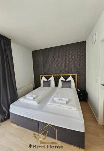 ein Schlafzimmer mit einem großen Bett mit weißer Bettwäsche und Kissen in der Unterkunft Bird Home Room 9 in Klagenfurt am Wörthersee