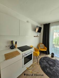 eine Küche mit weißen Schränken und einem gelben Stuhl in der Unterkunft Bird Home Room 9 in Klagenfurt am Wörthersee