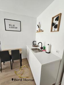 eine weiße Küche mit einem Waschbecken und einem Tisch in der Unterkunft Bird Home Room 9 in Klagenfurt am Wörthersee