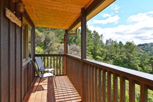 a porch with a chair and a view of the woods at Remutaka retreat in Upper Hutt