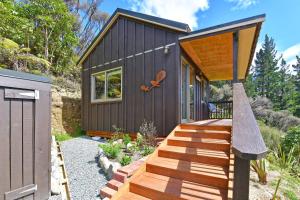 a small black house with a wooden deck at Remutaka retreat in Upper Hutt