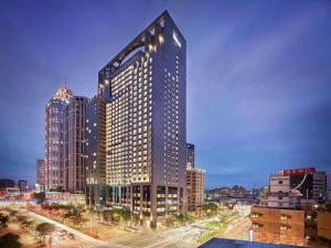 a tall building with many windows in a city at Hilton Taipei Sinban in Taipei