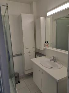 La salle de bains blanche est pourvue d'un lavabo et d'un miroir. dans l'établissement Appartement met prachtig zicht op zee, à Ostende