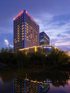 Un grand bâtiment avec des lumières allumées la nuit dans l'établissement Hilton Garden Inn Hangzhou Xixi Zijingang, à Hangzhou