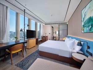 Habitación de hotel con cama, escritorio y TV. en Hilton Garden Inn Hangzhou Xixi Zijingang en Hangzhou