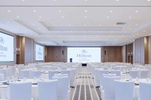 een conferentieruimte met witte stoelen en een projectiescherm bij Hilton Lijiang in Lijiang