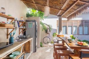 una cocina con nevera y mesas y sillas de madera. en Hostal Doña Lucha en Tulum