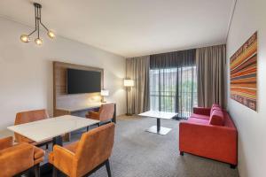 um quarto de hotel com uma mesa e cadeiras e uma televisão em DoubleTree by Hilton Alice Springs em Alice Springs