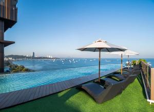 einen Pool mit 2 Liegestühlen und einem Sonnenschirm in der Unterkunft Hilton Pattaya in Pattaya