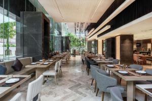 un restaurante con mesas y sillas de madera y ventanas en DoubleTree by Hilton Bangkok Ploenchit, en Bangkok