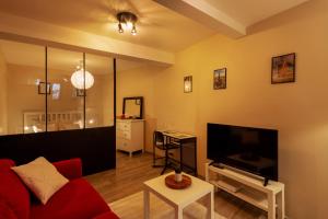 een woonkamer met een rode bank en een flatscreen-tv bij Appartement entier Strasbourg Centre in Straatsburg