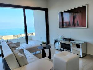 a living room with a white couch and a tv at Luxury Beachfront Condo in Rosarito with Pool & Jacuzzi in Rosarito