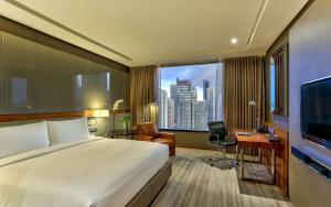 a hotel room with a bed and a desk and a window at Hilton Sukhumvit Bangkok in Bangkok