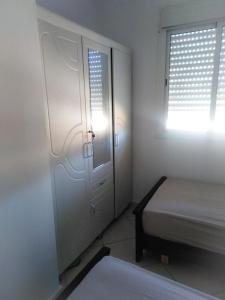 um quarto com uma porta, uma cama e uma janela em Appartement sur la route de la plage de Achakar em Tânger