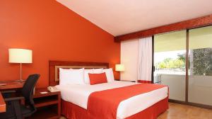 um quarto de hotel com uma cama, uma secretária e uma janela em Fiesta Inn Villahermosa Cencali em Villahermosa