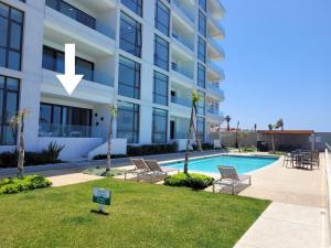 a view of a building with a pool and chairs at Seafront Luxury Condo in Rosarito with Pool & Jacuzzi in Rosarito