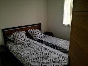 uma cama com lençóis e almofadas preto e branco em Bas de Maison em Biguglia