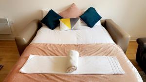 a bed with pillows and a towel on it at Mayfair - Duplex Relocations in Wakefield