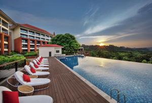 DoubleTree by Hilton Goa - Panaji في باناجي: مسبح المنتجع مع كراسي الصالة وغروب الشمس