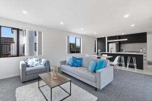 a living room with a couch and chairs and a kitchen at New 3bds house walk to Rototuna shopping Centre in Hamilton