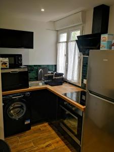eine Küche mit einer Waschmaschine, einer Spüle und einem Kühlschrank in der Unterkunft Bas de Maison dans le village in Biguglia