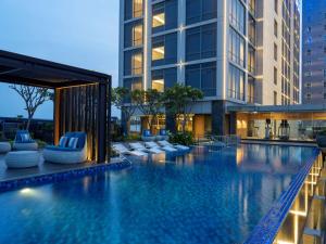 雅加達的住宿－Hilton Garden Inn Jakarta Taman Palem，一座带躺椅的游泳池和一座建筑