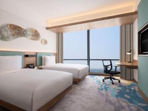 ein Hotelzimmer mit zwei Betten und einem Schreibtisch in der Unterkunft Hilton Garden Inn Jakarta Taman Palem in Jakarta