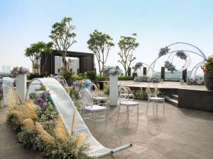 einen Garten mit Rutsche, Stühlen und Blumen in der Unterkunft Hilton Garden Inn Jakarta Taman Palem in Jakarta