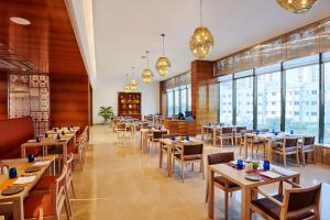 a restaurant with tables and chairs and windows at Hilton Garden Inn Lucknow in Lucknow