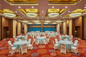 Hilton Garden Inn Lucknow في لاكناو: قاعة احتفالات كبيرة مع طاولات بيضاء وكراسي بيضاء