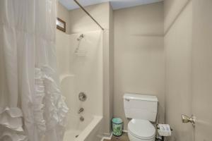 y baño blanco con aseo y ducha. en Sail House East by Vacation Homes Collection, en Gulf Shores
