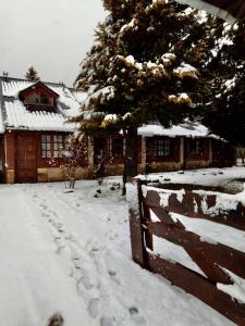 un patio cubierto de nieve con una valla y una casa en Nueva Serena, en San Carlos de Bariloche