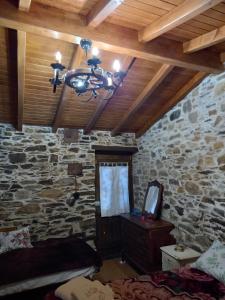 a bedroom with a stone wall and a chandelier at Ceira Cottage in Góis