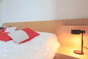 a bed with red and white pillows and a lamp at Borgo A Lago in Rezzonico