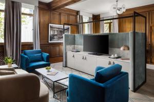 a living room with blue chairs and a tv at Hilton Melbourne Little Queen Street in Melbourne