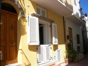 een geel gebouw met witte luiken en een deur bij Dorotea Studio in Lipari